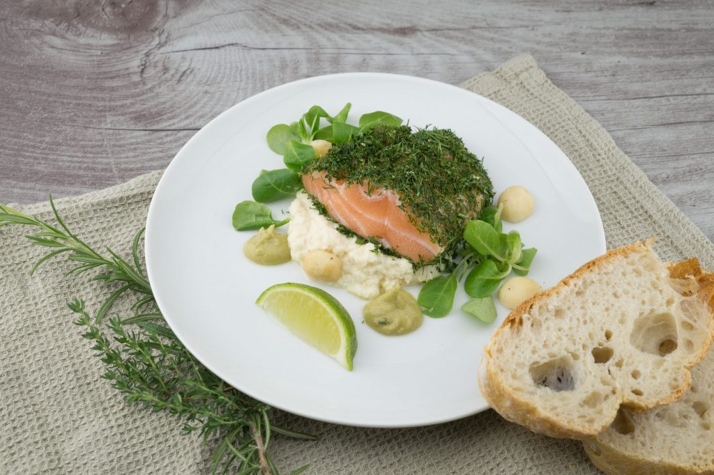 assiette blanche contenant saumon légumes et purée avec tranches de pain à côté