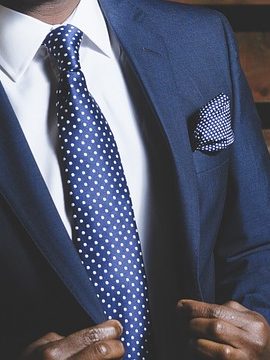zoom sur le buste d'un homme portant un costume bleu marine une chemise blanche et une cravate bleu marine