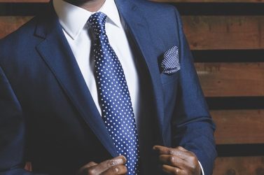 zoom sur le buste d'un homme portant un costume bleu marine une chemise blanche et une cravate bleu marine