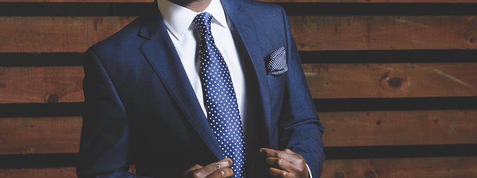 zoom sur le buste d'un homme portant un costume bleu marine une chemise blanche et une cravate bleu marine