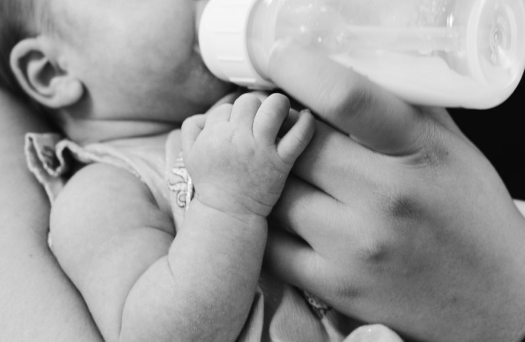 Jeune maman qui donne le biberon à son bébé