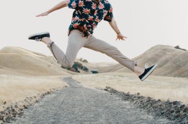 homme faisant un saut dans les airs portant un chino clair et une chemise à motifs floraux