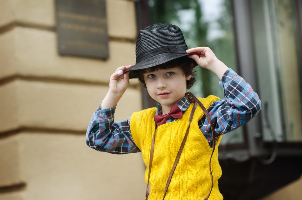 petit garçon qui porte un pull à manches courtes jaunes et un chapeau