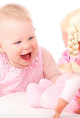 bébé qui sourit devant sa poupée